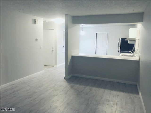 spare room featuring a textured ceiling, light hardwood / wood-style floors, and sink