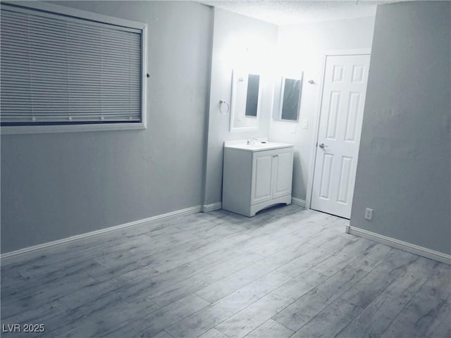 interior space with connected bathroom, a textured ceiling, and light wood-type flooring