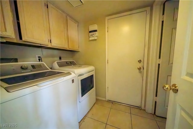 clothes washing area featuring washing machine and dryer, light tile patterned floors, and cabinets