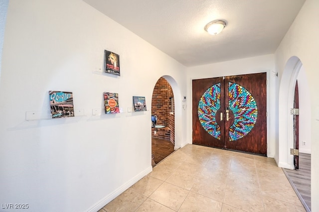 foyer with light tile patterned floors, a textured ceiling, and french doors