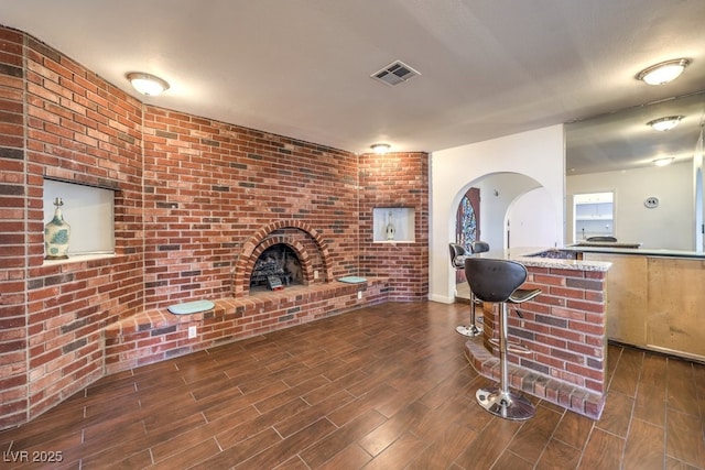 living room featuring brick wall, a textured ceiling, and a brick fireplace