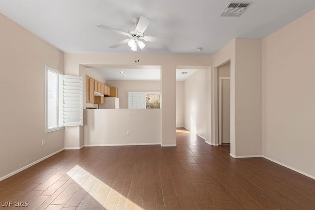 empty room with dark wood-type flooring, ceiling fan, and a healthy amount of sunlight