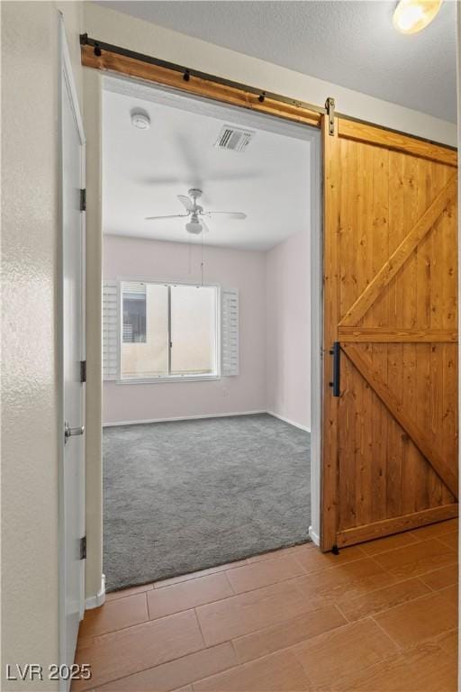 interior space featuring ceiling fan, carpet flooring, and a barn door