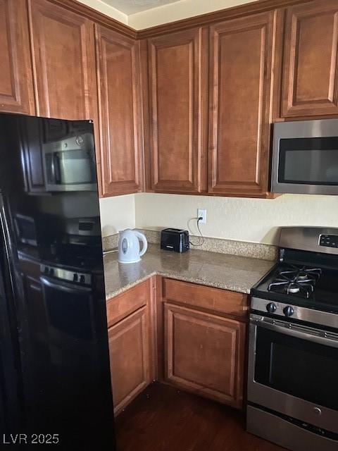 kitchen featuring light stone countertops, appliances with stainless steel finishes, and dark hardwood / wood-style floors