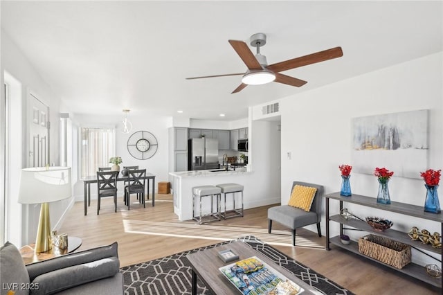 living room with light hardwood / wood-style floors, ceiling fan, and sink