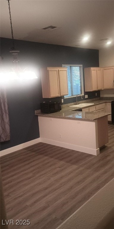 kitchen with kitchen peninsula, decorative light fixtures, dark hardwood / wood-style floors, and sink