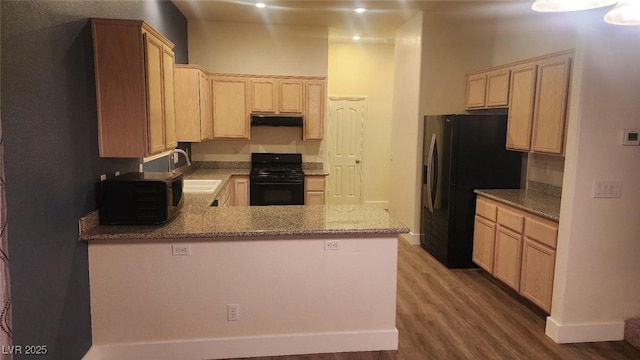 kitchen featuring hardwood / wood-style floors, black appliances, sink, light brown cabinetry, and kitchen peninsula