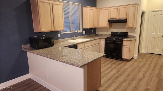 kitchen featuring kitchen peninsula, light stone counters, sink, black appliances, and light brown cabinets