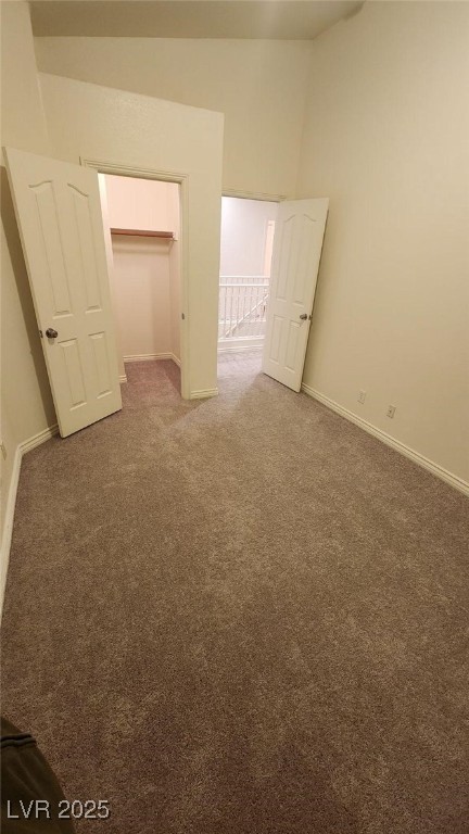 unfurnished bedroom with a spacious closet, dark carpet, and a closet