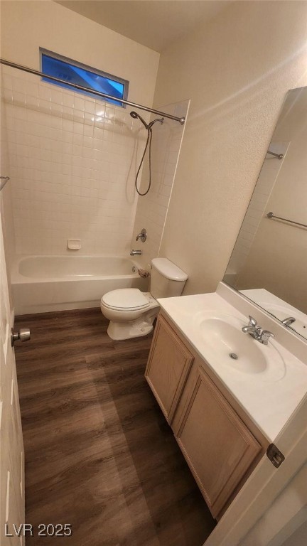 full bathroom featuring hardwood / wood-style flooring, vanity, toilet, and tiled shower / bath combo