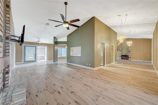 unfurnished living room featuring ceiling fan with notable chandelier, a textured ceiling, light wood-type flooring, and high vaulted ceiling