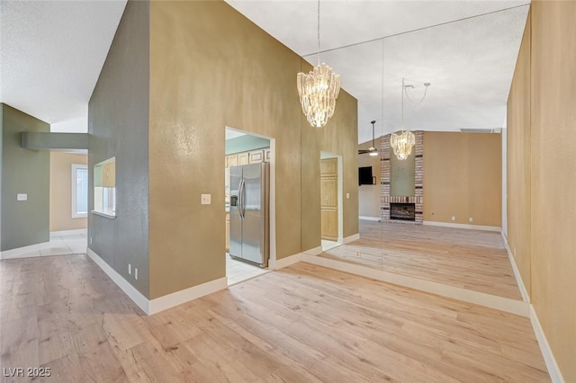 hall with a chandelier, light wood-type flooring, and high vaulted ceiling