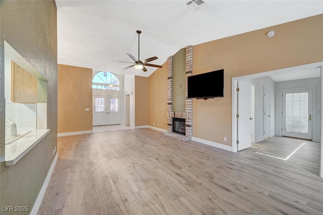 unfurnished living room featuring ceiling fan, french doors, light hardwood / wood-style floors, and vaulted ceiling