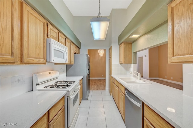 kitchen featuring sink, light tile patterned floors, light brown cabinetry, appliances with stainless steel finishes, and decorative light fixtures