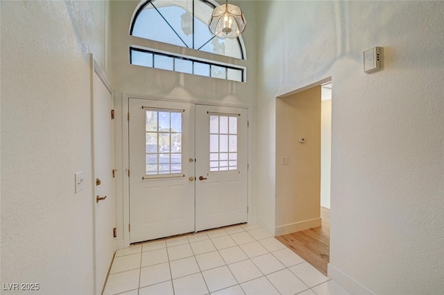 foyer entrance featuring french doors, light tile patterned flooring, and a high ceiling