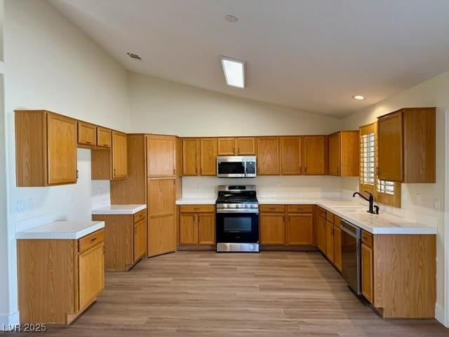 kitchen with sink, high vaulted ceiling, light wood-type flooring, and appliances with stainless steel finishes