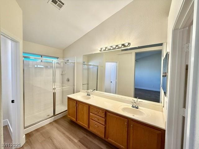 bathroom featuring hardwood / wood-style floors, a shower with shower door, lofted ceiling, and vanity