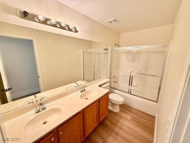 full bathroom with toilet, vanity, enclosed tub / shower combo, and hardwood / wood-style flooring