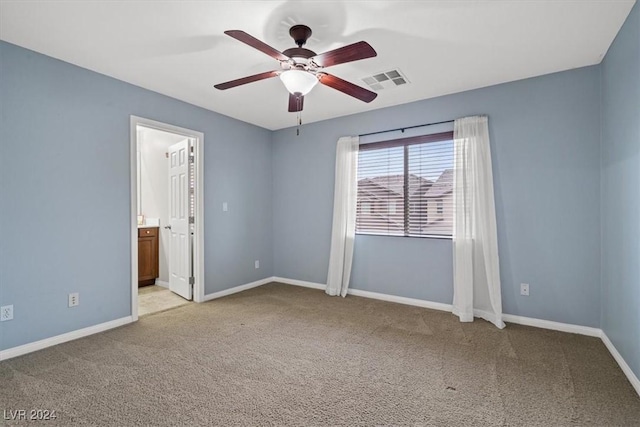 unfurnished bedroom with light carpet, ensuite bathroom, and ceiling fan