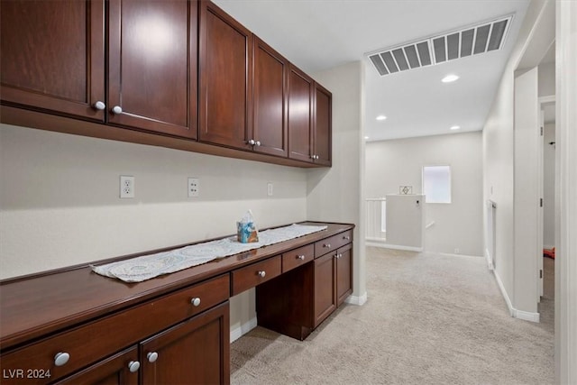 interior space with built in desk and light colored carpet