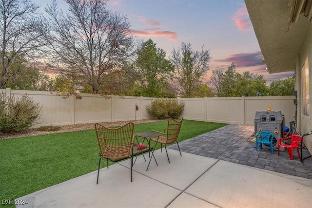 patio terrace at dusk featuring a yard