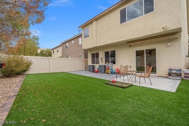 back of property with central air condition unit, a patio area, and a lawn