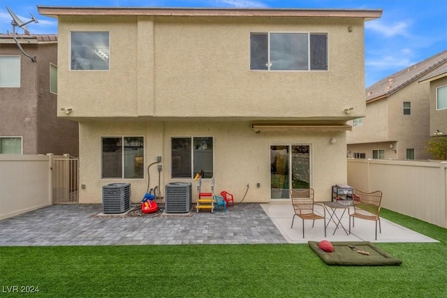 rear view of house featuring central AC unit, a yard, and a patio