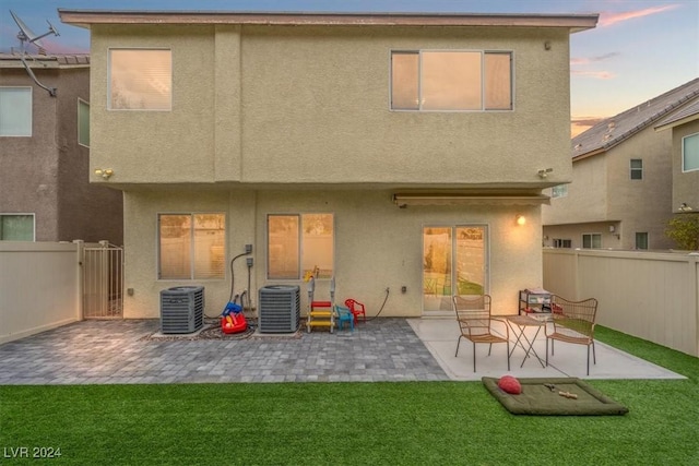 back house at dusk with a patio area and central AC unit