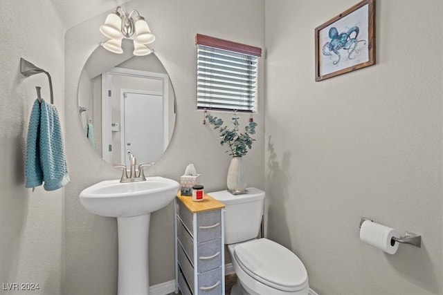 bathroom with sink, a notable chandelier, and toilet