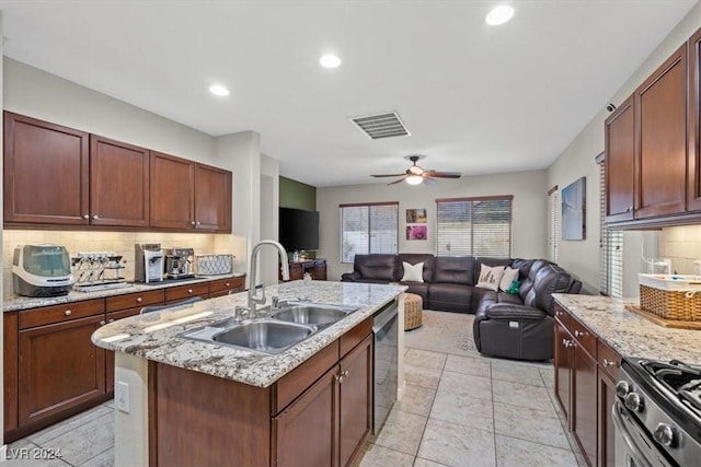 kitchen featuring decorative backsplash, appliances with stainless steel finishes, ceiling fan, a kitchen island with sink, and sink