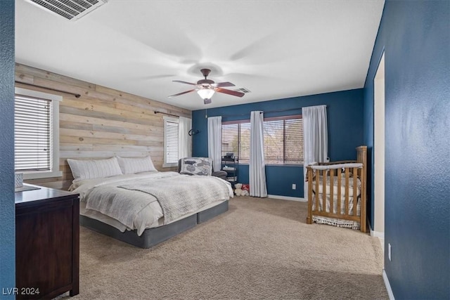 bedroom with carpet flooring, ceiling fan, and wood walls