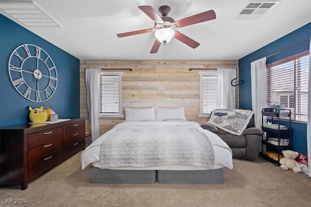 bedroom featuring ceiling fan, wood walls, and light carpet