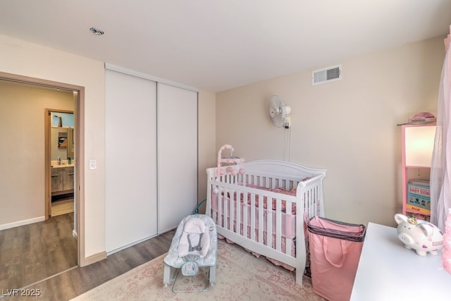 bedroom featuring dark hardwood / wood-style floors, a crib, and a closet