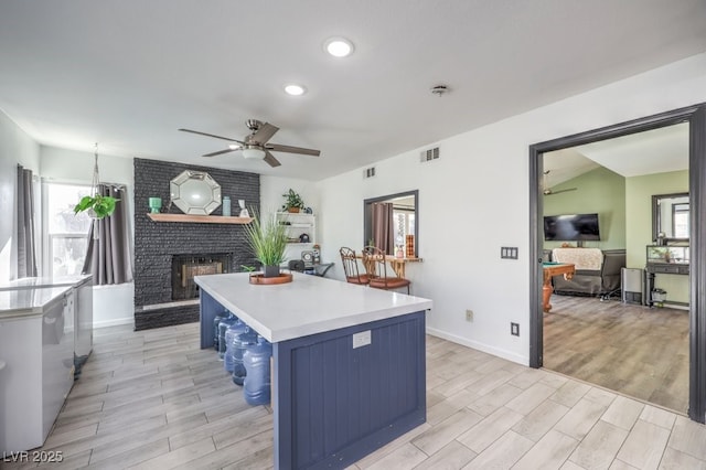 kitchen with a kitchen island, a healthy amount of sunlight, a breakfast bar area, and a brick fireplace