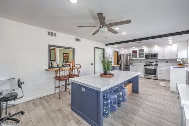 kitchen featuring sink, a breakfast bar area, a center island, stainless steel appliances, and white cabinets