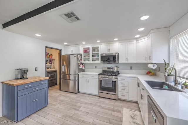 kitchen with white cabinetry, wood counters, and stainless steel appliances