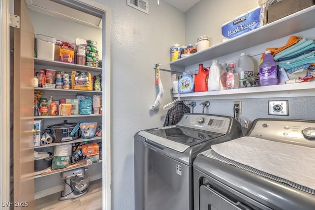 laundry room with wood-type flooring and separate washer and dryer