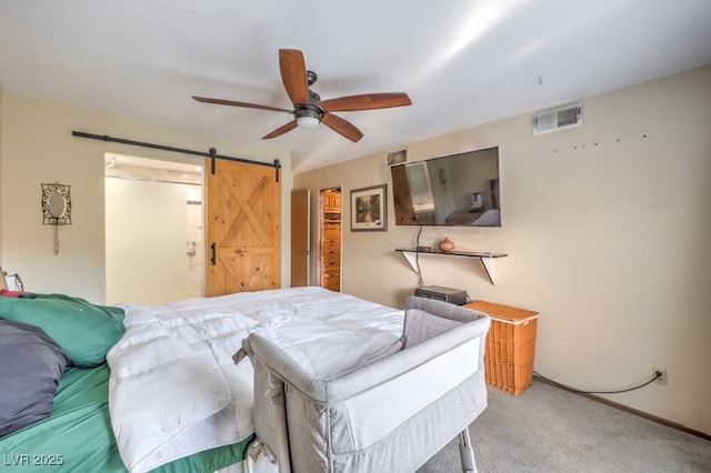 carpeted bedroom featuring ceiling fan and a barn door