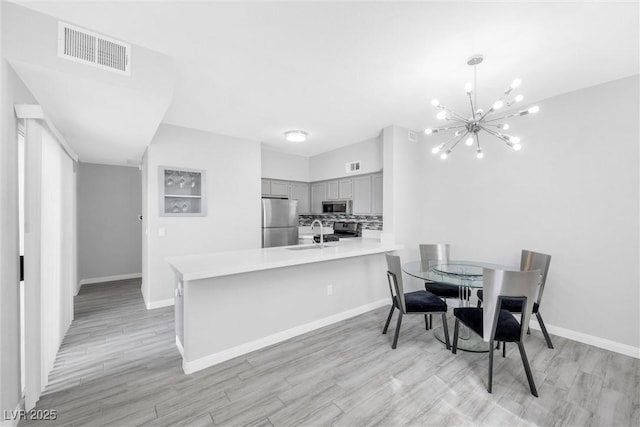 dining area with light hardwood / wood-style flooring, an inviting chandelier, and sink