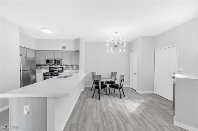 kitchen featuring kitchen peninsula, appliances with stainless steel finishes, decorative light fixtures, and sink