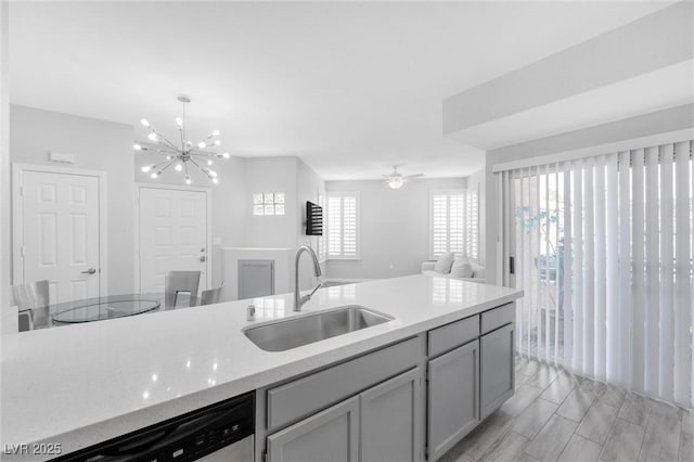 kitchen with ceiling fan with notable chandelier, gray cabinets, sink, and a wealth of natural light