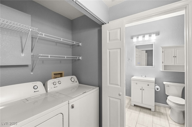 clothes washing area with sink, light tile patterned floors, and independent washer and dryer