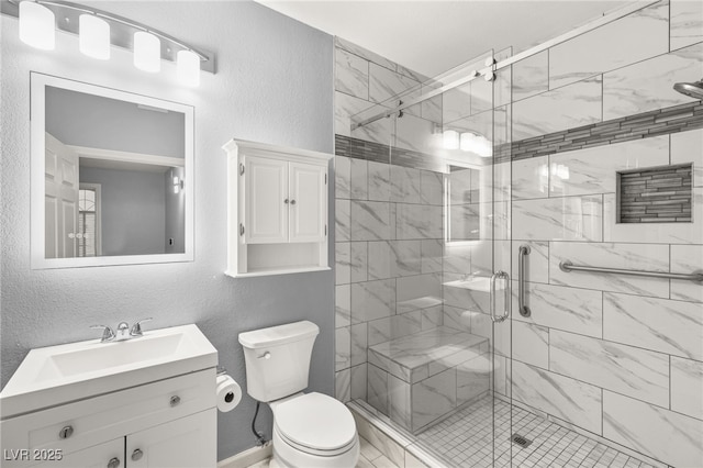 bathroom featuring vanity, a shower with shower door, and toilet