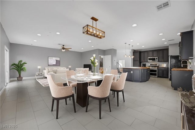 dining room with sink, light tile patterned floors, and ceiling fan with notable chandelier