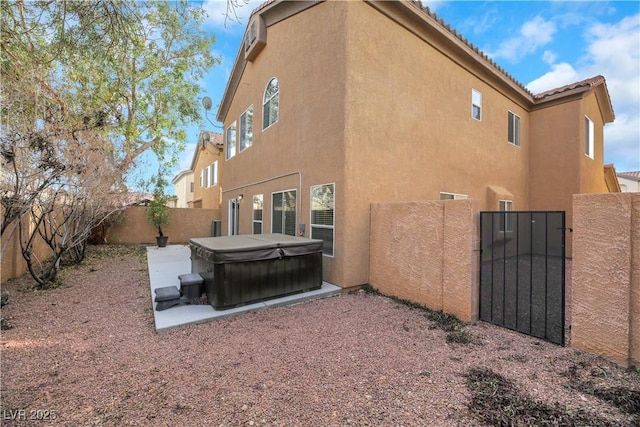 rear view of property featuring a patio and a hot tub