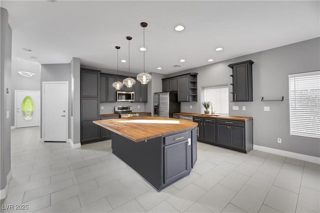 kitchen with gray cabinetry, pendant lighting, a center island, appliances with stainless steel finishes, and butcher block countertops