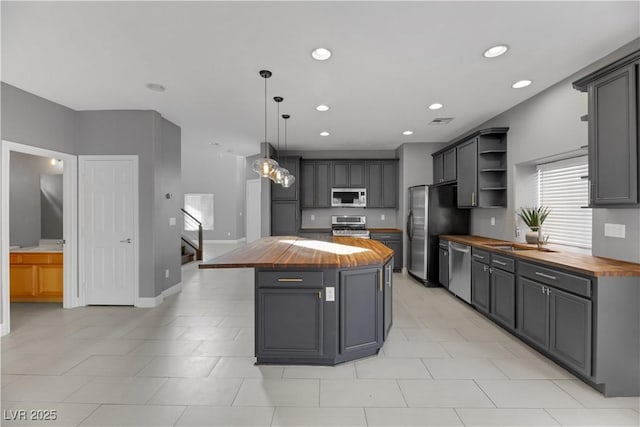 kitchen featuring butcher block counters, a center island, gray cabinets, and stainless steel appliances