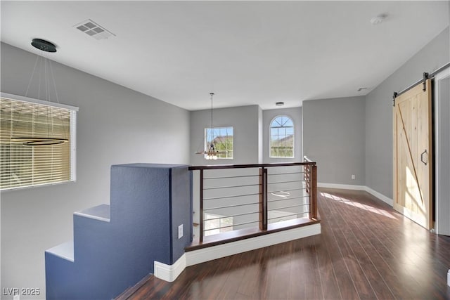 empty room with a barn door and dark hardwood / wood-style floors