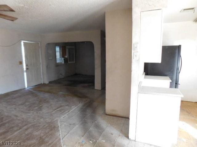 interior space featuring a ceiling fan, visible vents, and a textured ceiling