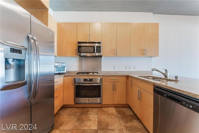 kitchen featuring light brown cabinets, sink, decorative backsplash, light stone counters, and stainless steel appliances